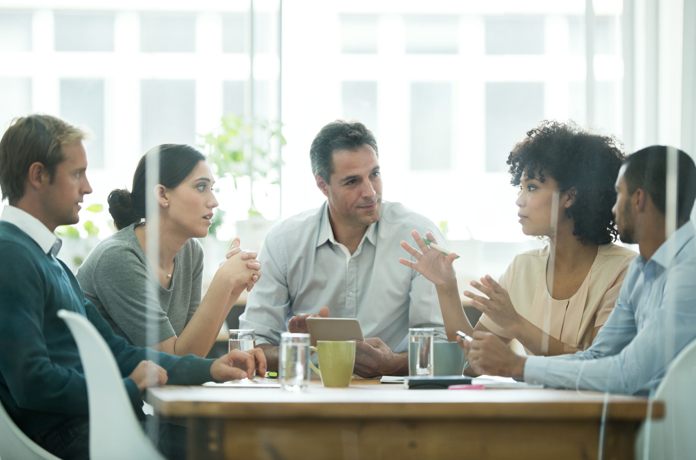 Un groupe de cinq personnes assises autour d’une table, dans un contexte professionnel