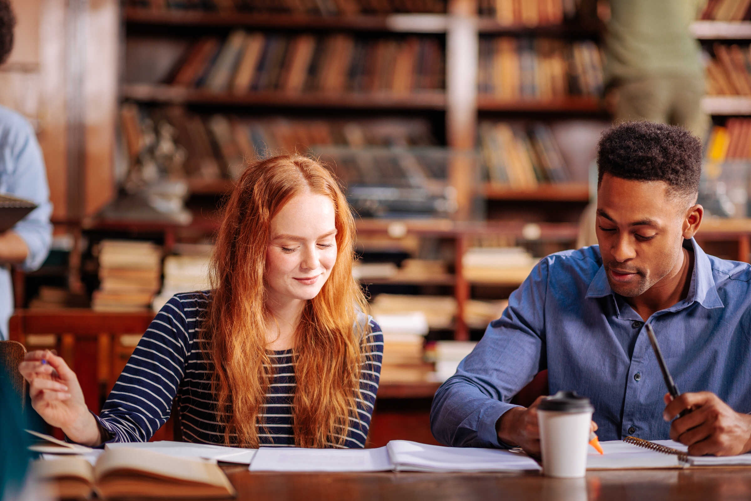 Deux étudiants sont assis à une table et regardent leurs cahiers