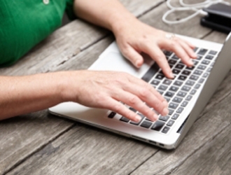 A person's hands typing on a Macbook keyboard at a desk