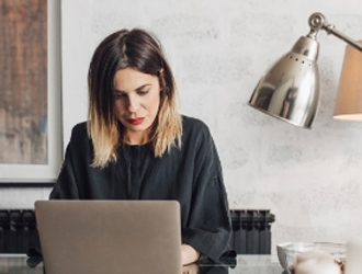 A woman sitting at a desk working on her Macbook