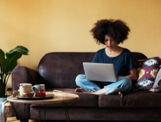 A woman sitting down on a leather sofa working on her Mac laptop
