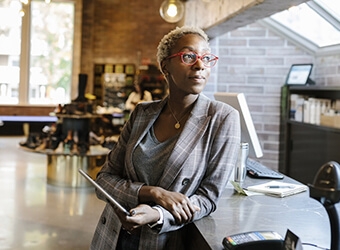 A person leaning on a counter while holding a tablet device