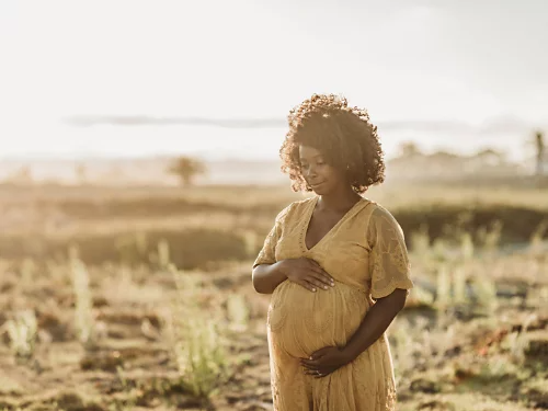 A solo maternity photo taken during golden hour.