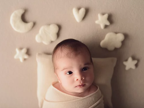 A photo of a newborn baby with fabric shapes used as props.
