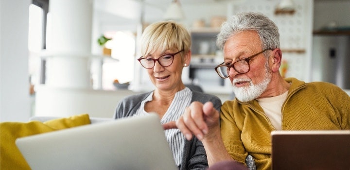 Foto eines älteren Paares, die gemeinsam etwas auf einem Laptop lesen.