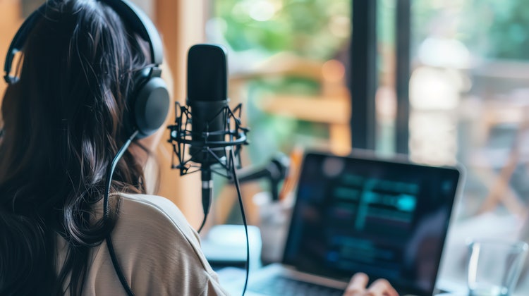 Eine Frau veröffentlicht einen Podcast an ihrem Laptop.