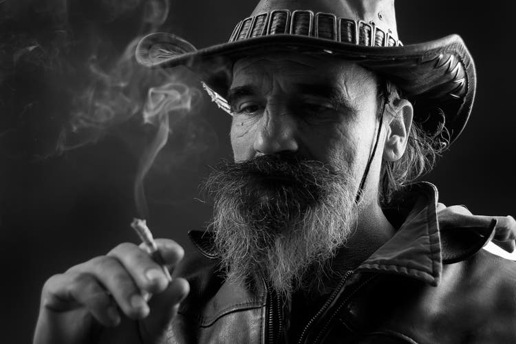 Eine extreme Nahaufnahme des Profils eines Cowboys, der eine Zigarre raucht