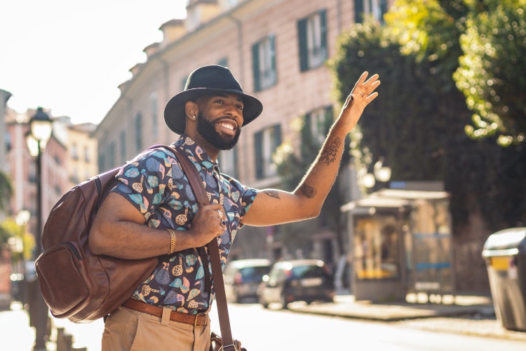 Stylish gekleideter Mann mit Hut und Rucksack auf der Straße