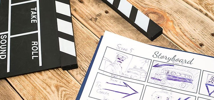Das Bild zeigt einen Holztisch mit einer Filmklappe oben links und rechts daneben ein Storyboard mit Skizzen von verschiedenen Szenen