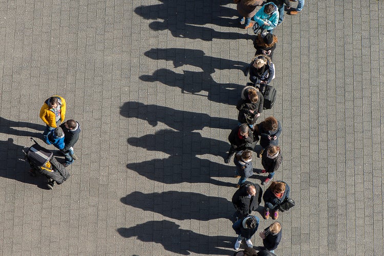 Vogelperspektive mit steilem Winkel auf Menschen, die in einer Schlange warten.