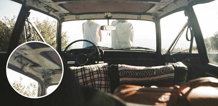 Altes Autointerieur mit Personen, die auf der Motorhaube sitzen; mit Filmkörnung