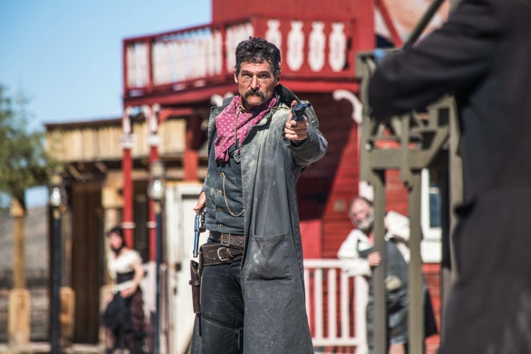 Sheriff mit gezogenem Revolver zielt in der Amerikanischen Einstellung auf seinen Gegner