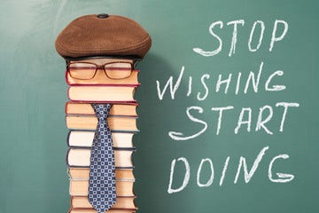 Slogan neben einem Bücherstapel mit Brillen, Krawatte und Hut.