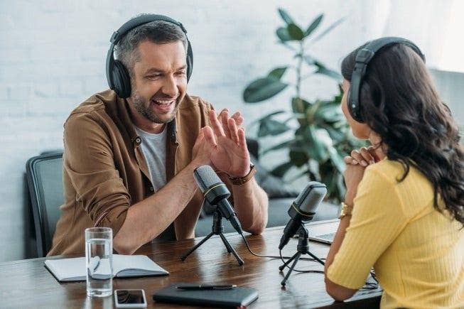 Two people recording a podcast with a glass of water next to them