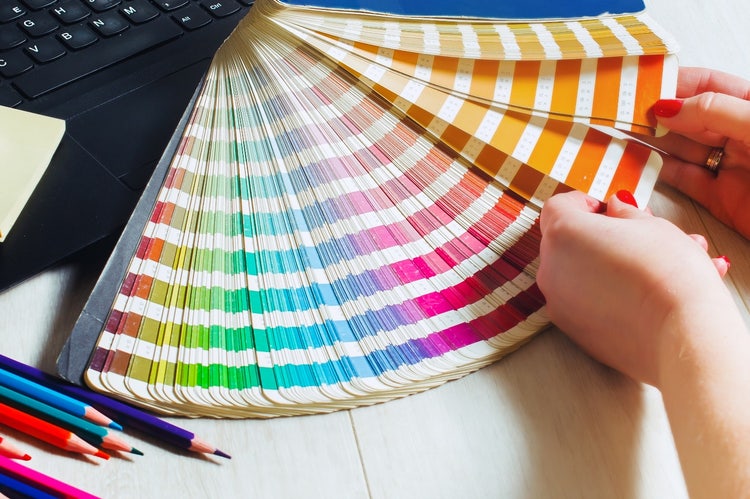 Grafiker blättert durch eine Farbreferenztabelle.