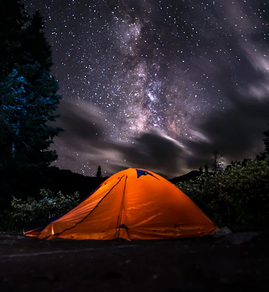 Ein Foto eines Campingzelts bei Nacht. Der Himmel ist voller Sterne.