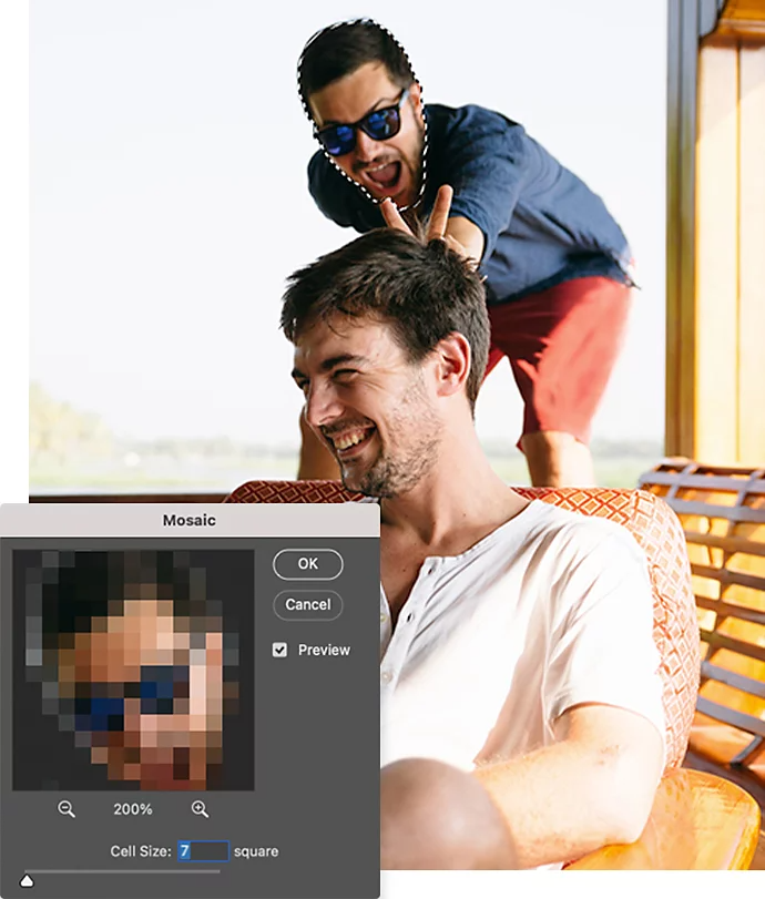 Et billede af en person, der laver kaninører bag en anden person, der sidder i en stol, med Adobe Photoshop-mosaic-indstillingsvinduet lagt henover