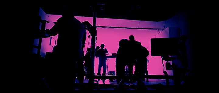 Silhouette image of film crew lit by neon light.