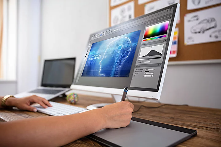 Close up of person drawing on design pad with editing software on computer monitor.