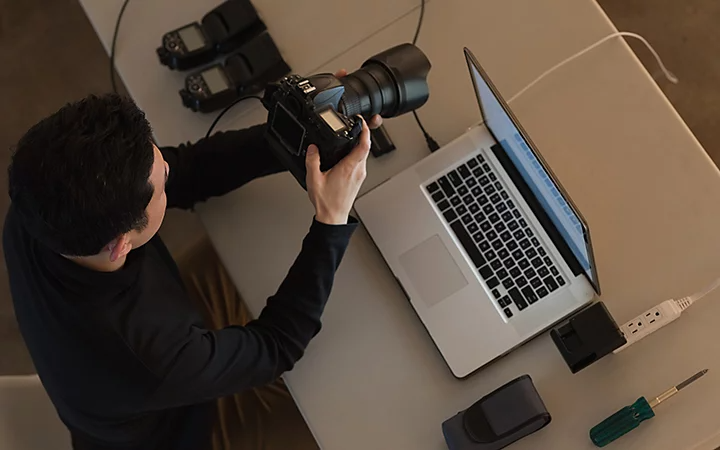A photographer checking the flash on their camera and other equipment at a desk