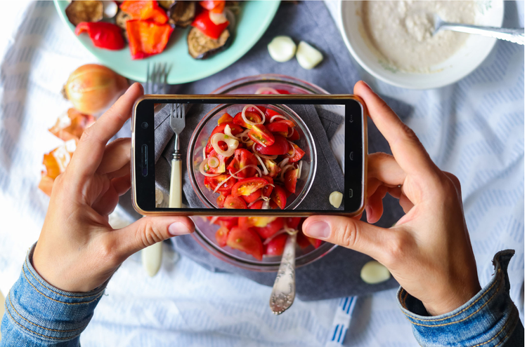 food picture A pair of hands hold a phone over a plate of red-colored food to take a picture.