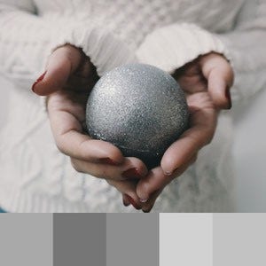 A color palette created from a close up image of a person in a white sweater holding a grey ball in their hands
