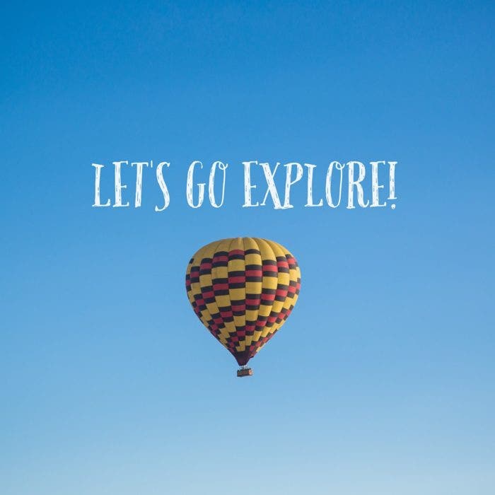 A hot air balloon floating in a clear blue sky. Above the balloon, reads "Lets go explore".