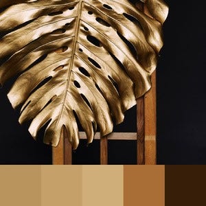 A color palette created from an image of a gold leaf with a wooden structure behind it against a dark background
