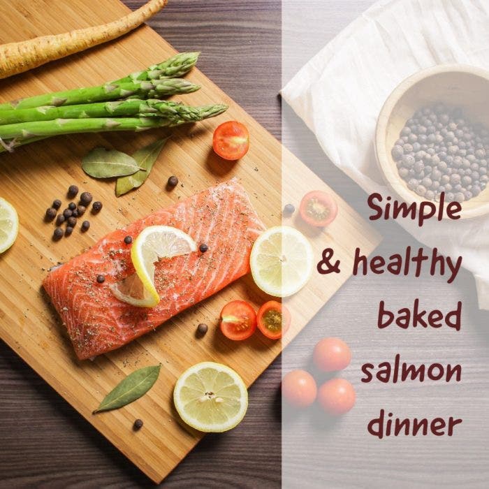 Asparagus, tomato, salmon and lemon on a wooden table. The text reads "Simple & healthy baked salmon dinner"