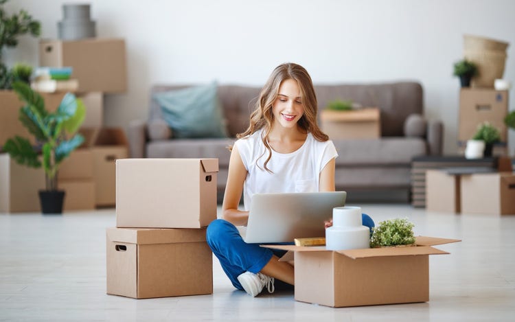 How to sell my house: A woman using a laptop while packing boxes