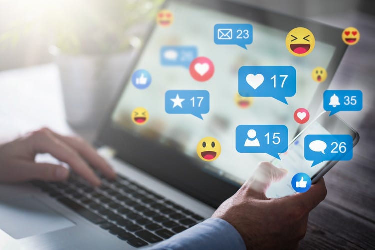 A computer with various Facebook icons popping out of the screen such as likes, follows, and comments