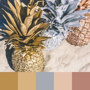 A color palette created from an image of gold, rose gold, and silver pineapples in the sand