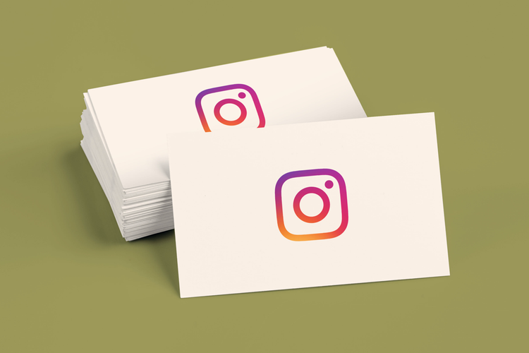 A stack of white business cards with the Instagram logo on them against a green background