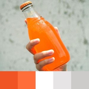 A color palette created from an image of a hand holding clear bottle filled with an orange liquid against a grey background