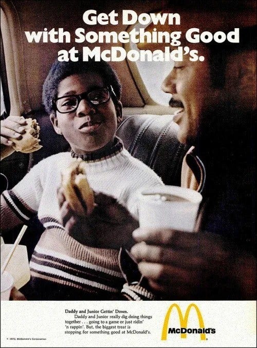 Colorful photographic image of a young Black child and Black man eating burgers in a vehicle. The tagline at top reads "Get Down with Something Good at McDonald's."