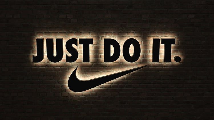 Nike slogan with logo backlit against a brick wall