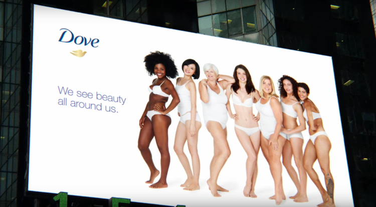 A Dove marketing billboard with 7 diverse people smiling and posing in underwear with the words "Dove. We see beauty all around us."