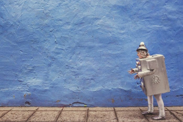 A person wearing a robot costume, in front of a blue wall.