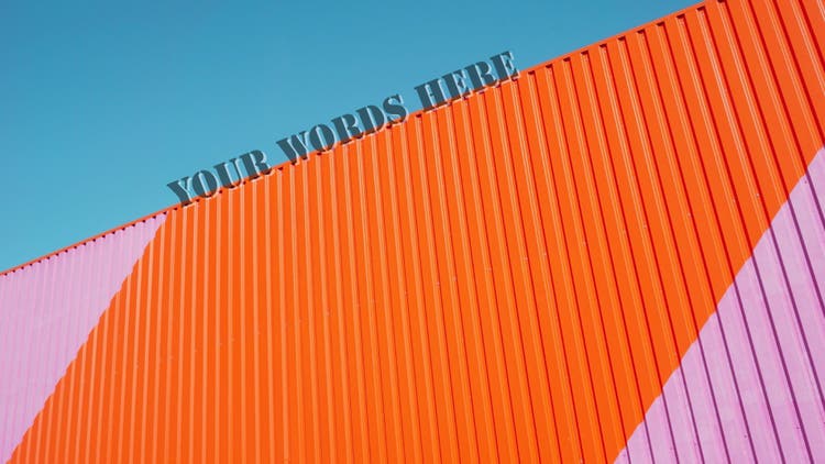 Orange and pink colorful corrugated surface. Above, there is a clear blue sky and at the top, the text "Your words here"