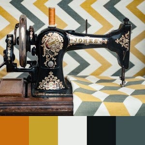 A color palette created from an image of an old black and gold sewing machine against a blue-grey, yellow, and white striped background