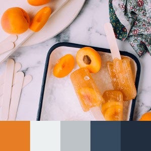 A color palette created from an image of peaches and orange popsicles in an ice bucket against a white marble countertop