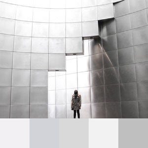 A color palette created from an image of a person standing in a silver block structure with the sun casting shadows