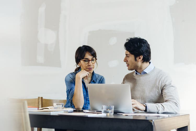 A property owner and property manager reviewing a property management agreement on a laptop together