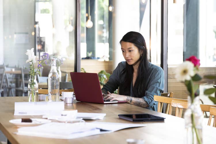A marketer sitting at a table creating a marketing proposal on their laptop