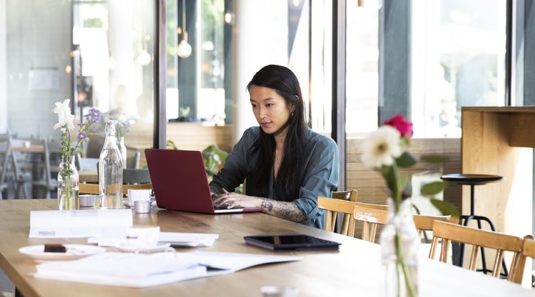 A marketer sitting at a table creating a marketing proposal on their laptop