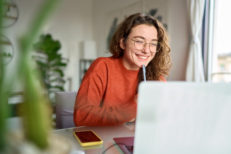Étudiante souriant devant son ordinateur en train de relire la conclusion de son mémoire.