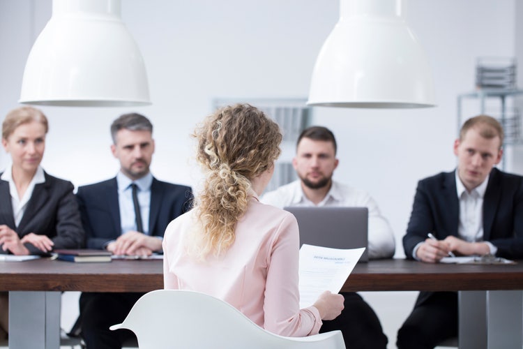 Étudiante en train de faire sa soutenance de mémoire devant un jury avec ses notes dans les mains.