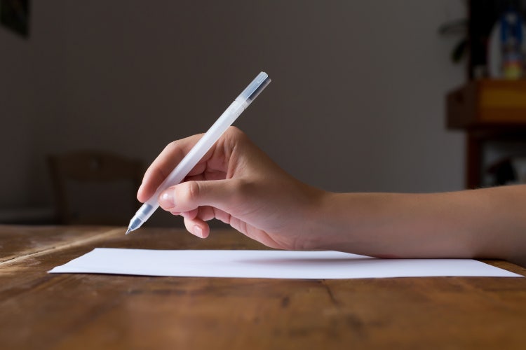 Une personne écrit une lettre de motivation à la main.