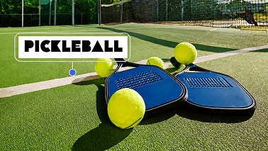 Raquettes et balles de pickleball sur le court, illustrant la section « Partez à la conquête des réseaux sociaux. »