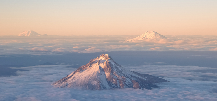 Vue aérienne de montagnes perçant les nuages sous un ciel clair
